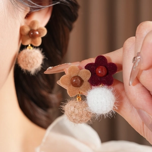 Detail of floral flocked earrings with soft plush pom poms and elegant pearl accents