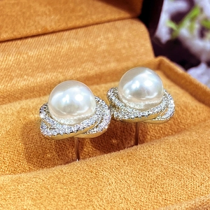 Macro detail of pearl earrings with zircon encrusted floral spiral design in silver