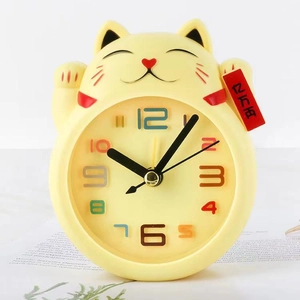 Detail of yellow lucky cat alarm clock with colorful numeric dial and red charm