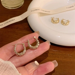 Close-up of gold and silver hollow star-shaped earrings with intricate U-shaped design