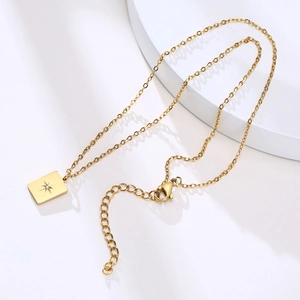 Detail of gold rectangular pendant with starburst engraving and sparkling crystal