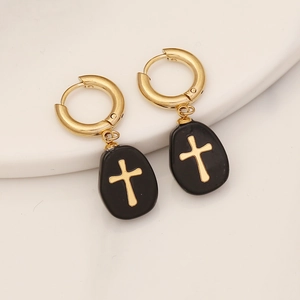 Close-up of gold cross earrings with black oval drop pendants on white background
