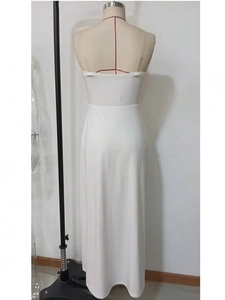 Detail of the back view of a white backless maxi dress with cross strap and high slit