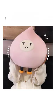 Soft pink peach plush toy with embroidered sad face and dangling orange legs detail