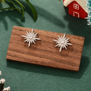 Close-up of star-shaped zircon earrings on a wooden display with a festive background