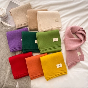 Flat lay of colorful knitted scarves in various candy colors on white fabric background