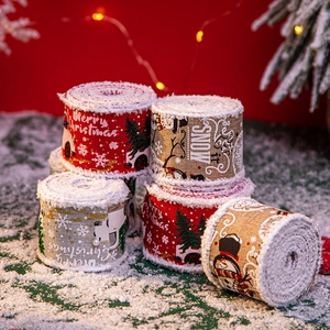 Christmas burlap ribbon with snowman patterns displayed on snow with warm lights