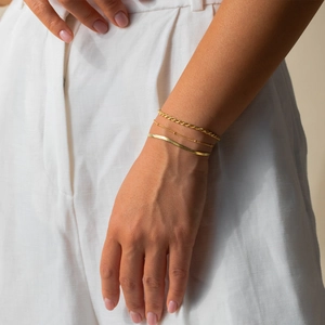 Detailed view of triple-layered 18K gold Figaro and snake chain bracelets for women