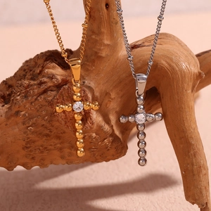 Detail of beaded cross pendant in gold and silver finish with central zircon inlay