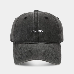 Dettaglio del ricamo LOW KEY bianco su cappellino in cotone nero lavato vintage