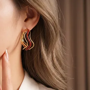 Irregular wavy hoop earrings in gold and reddish-brown enamel for a modern luxury look