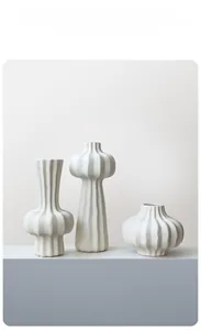 Detailed close-up of set of 3 modern white matte ceramic vases with vertical ribbed texture