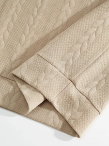Close-up of beige knit fabric texture with intricate cable stitch and honeycomb patterns