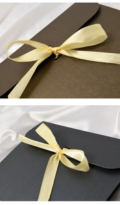 Detail of elegant envelope gift boxes with satin ribbons on white silk background