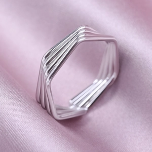 Macro detail of 304 stainless steel hexagonal layered ring on purple silk fabric