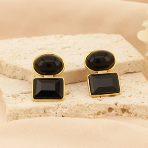 Macro shot of vintage black square double-layer earrings on stone texture