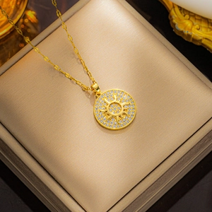Luxurious gold sun disc necklace with zircon pavé pendant in a beige jewelry box