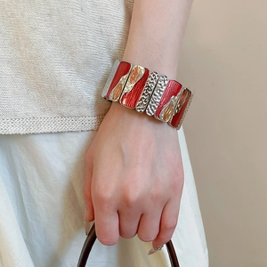 Detail of red and gold enamel metal elastic bracelet with hammered texture finish