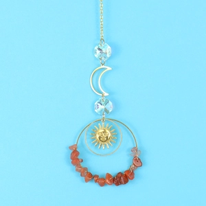 Detail of sun catcher with red gravel ring, moon and sun face metal pendants