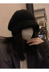 Close-up of black chunky knit bucket hat showing textured wool and oversized fit design