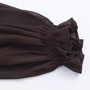 Detail of smocked elastic cuffs on dark brown long sleeve dress with crepe fabric texture