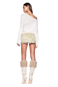 Rear view of long sleeve off-shoulder knit top with denim mini skirt and fur-trimmed boots