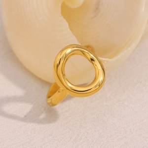 Anello geometrico cavo in acciaio inossidabile placcato oro 18K esposto su una conchiglia