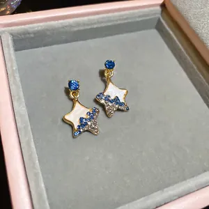Star-shaped earrings with white enamel and blue crystals in a pink jewelry box