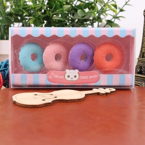 Set of four colorful donut-shaped erasers in clear gift box on a wooden desk