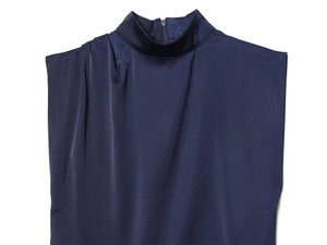 Dettaglio abito in raso blu navy con collo alto, zip sul retro e tessuti a pieghe