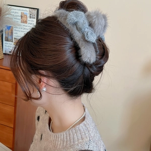 Detail of plush grey faux fur hair claw clip worn in a messy bun for winter style