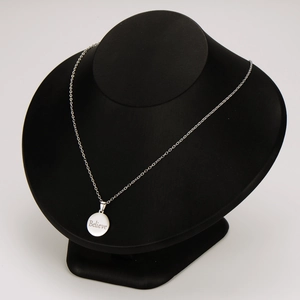 Stainless steel round pendant necklace with Believe engraving on a black mannequin display