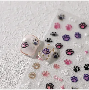 Macro detail of 3D embossed paw print nail stickers in vibrant colors on a textured surface