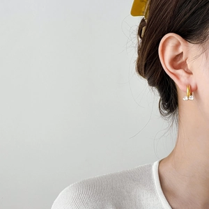 Detail of golden U-shaped earrings with twin transparent heart crystals on model