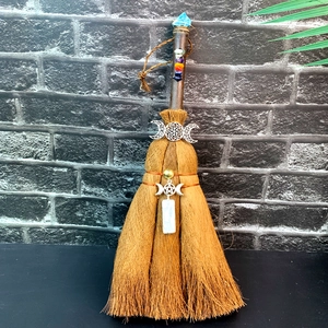 Close-up of decorative brown witch broom with natural crystals and moon charms