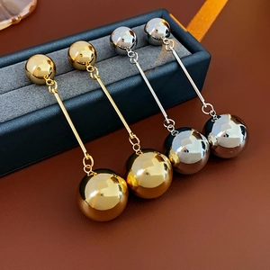 Macro detail of gold and silver metallic geometric tassel earrings in a jewelry box