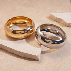 Polished gold and silver metal bangles displayed on textured natural stone blocks