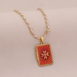 Détail d'un collier tressé en or avec pendentif trèfle tarot en émail rouge