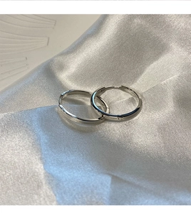 Polished S925 sterling silver hoop earrings displayed on white silk with plaster decor