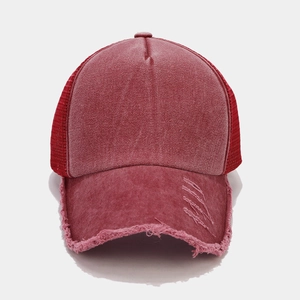Dettaglio macro del cappello trucker rosso slavato con rete traspirante e strappi