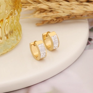 Detailed macro of gold-plated hoop earrings with sparkling crystals and a heart charm