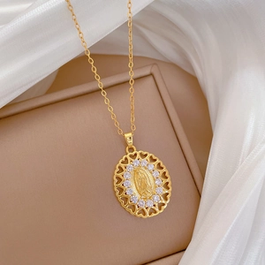 Macro detail of gold oval Virgin Mary pendant with white zircons and hollow heart frame