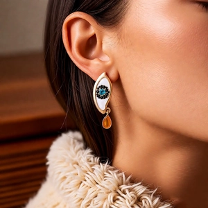 Close-up of vintage teardrop earrings with blue evil eye stone on knitted fabric