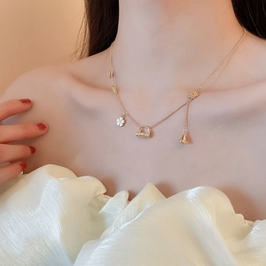 Detail of 18k gold plated necklace with flower and handbag pendants on model neck
