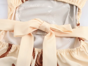 Detail of the oversized back bow tie on a palm print halter dress in beige and brown