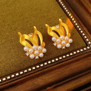 Vintage gold bow earrings with white pearls and zircons on a dark green background