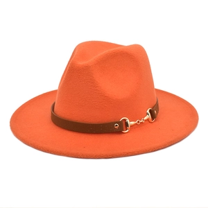 Detail of bright orange wool fedora featuring a brown leather band and gold horsebit buckle