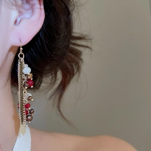 Detail of elegant long tassel earrings with red and white crystal beads on a model