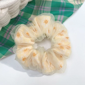 Detailed view of yellow polka dot organza scrunchie with white floral print on white background