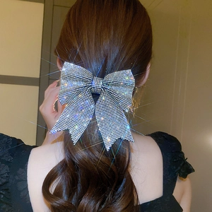 Detailed view of an elegant crystal bow hair clip worn on wavy brown hair